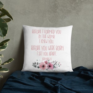 May include: White throw pillow with a floral design and the text "BEFORE I FORMED YOU IN THE WOMB I KNEW YOU. BEFORE YOU WERE BORN I SET YOU APART. JEREMIAH 1:5"