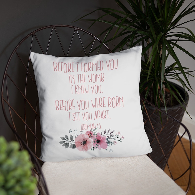 May include: White throw pillow with a floral design and the text "BEFORE I FORMED YOU IN THE WOMB I KNEW YOU. BEFORE YOU WERE BORN I SET YOU APART. JEREMIAH 1:5"
