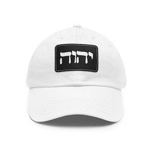 May include: White baseball cap with a black patch featuring the Hebrew word "Shabbat" in white lettering.