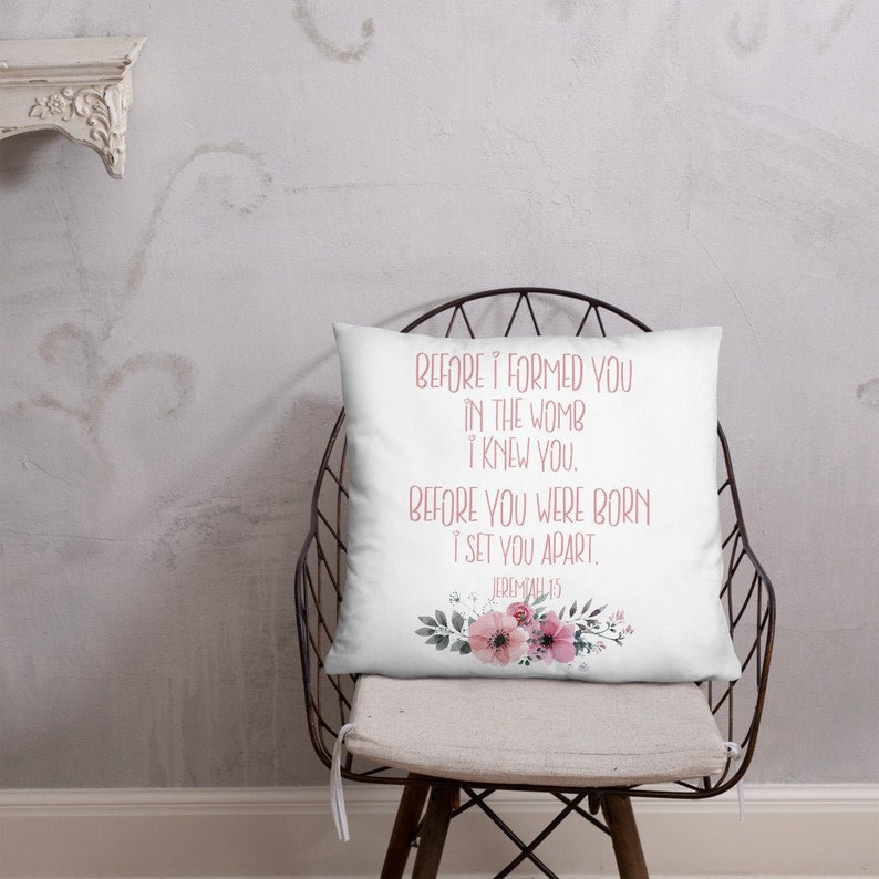 May include: White throw pillow with a floral design and the text "BEFORE I FORMED YOU IN THE WOMB I KNEW YOU. BEFORE YOU WERE BORN I SET YOU APART. JEREMIAH 1:5" in pink lettering.