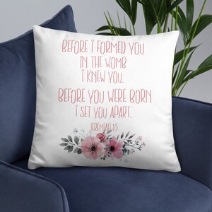 May include: White throw pillow with a pink floral design and the text "BEFORE I FORMED YOU IN THE WOMB I KNEW YOU. BEFORE YOU WERE BORN I SET YOU APART. JEREMIAH 1:5"