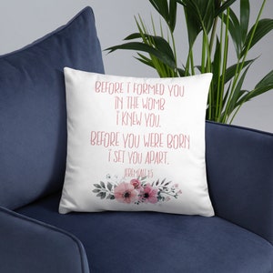 May include: White throw pillow with a floral design and the text "BEFORE I FORMED YOU IN THE WOMB I KNEW YOU. BEFORE YOU WERE BORN I SET YOU APART. JEREMIAH 1:5"
