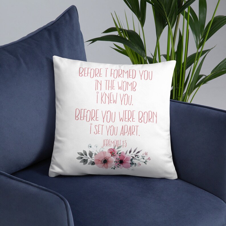 May include: White throw pillow with a floral design and the text "BEFORE I FORMED YOU IN THE WOMB I KNEW YOU. BEFORE YOU WERE BORN I SET YOU APART. JEREMIAH 1:5"