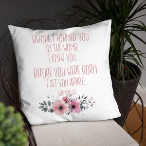 May include: White throw pillow with a pink floral design and the text "BEFORE I FORMED YOU IN THE WOMB I KNEW YOU. BEFORE YOU WERE BORN I SET YOU APART. JEREMIAH 1:5"