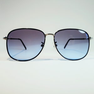 Puede incluir: Gafas de sol aviador negras con montura dorada y lentes azules degradados.