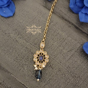May include: Gold chain with a blue and white stone pendant. The pendant has a round design with a blue stone in the center and white stones around it. The chain is attached to the pendant with a small loop.