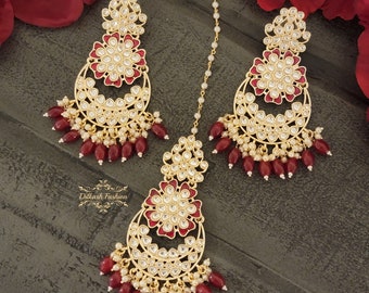 May include: A set of gold-tone earrings and a matching maang tikka, featuring intricate floral designs with red enamel accents and pearl and red bead embellishments.