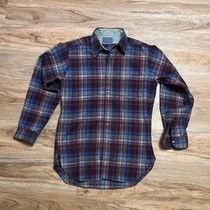 May include: A long-sleeved plaid shirt with a button-down collar. The shirt is made of a soft, brushed fabric and has a relaxed fit. The plaid pattern is in shades of red, blue, and gray.