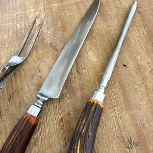 Puede incluir: Un juego de trinchar vintage que incluye un cuchillo largo para trinchar, una chaira y un tenedor para trinchar. Los mangos son de material marr&oacute;n oscuro con un dise&ntilde;o texturizado y el juego tiene detalles met&aacute;licos plateados.