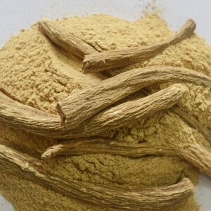 May include: A pile of light brown ginseng powder with several pieces of dried ginseng root on top.