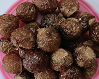 May include: A pink bowl filled with brown soap nuts. The soap nuts are a natural alternative to laundry detergent.