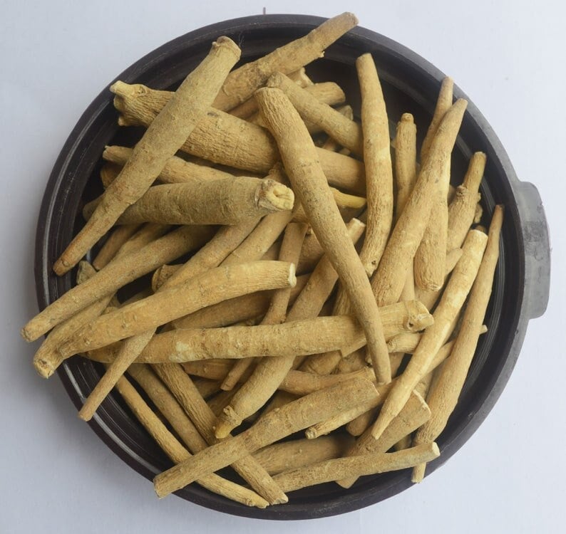 May include: A bowl filled with dried, light brown, thin, and long pieces of a root, likely a medicinal herb.