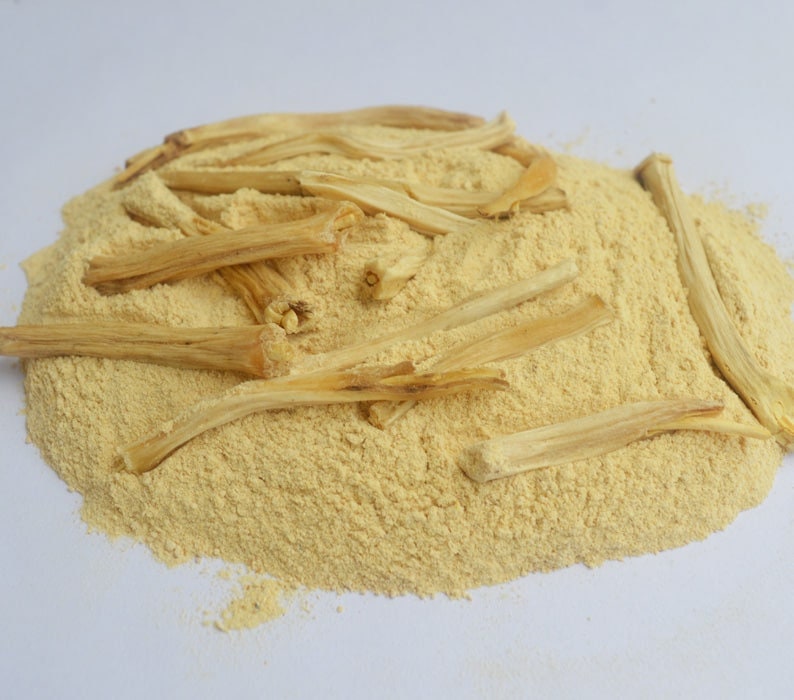May include: A pile of light yellow powder with several long, thin, light brown sticks on top.