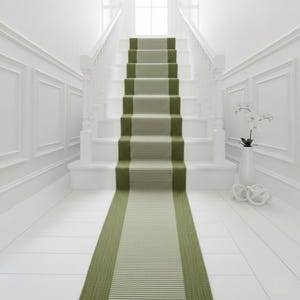 May include: A white staircase with a green and beige striped runner. The runner extends down the hallway, matching the stair treads. White walls and trim create a bright, clean aesthetic. A vase with white flowers sits on the floor.