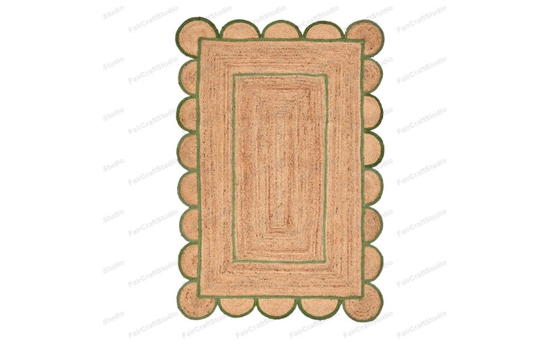 May include: A rectangular jute rug with a green border and scalloped edges. The rug has a smaller green rectangle in the center.