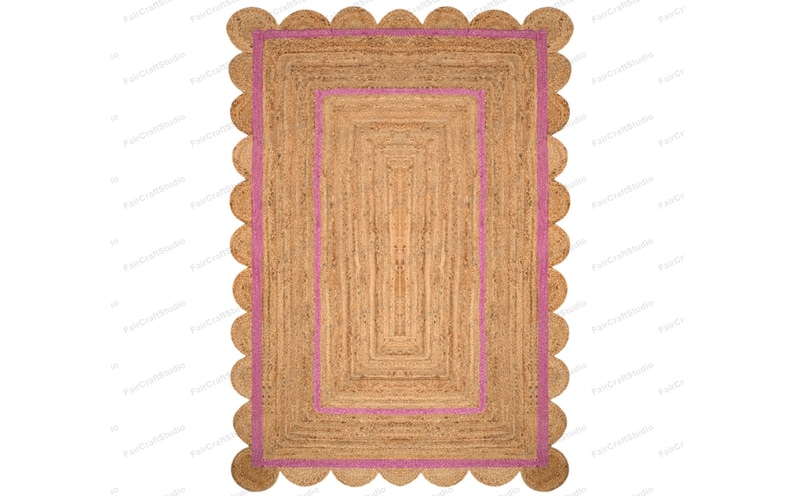 May include: A rectangular jute rug with a pink border and scalloped edges. The rug has a woven texture and a natural brown color.