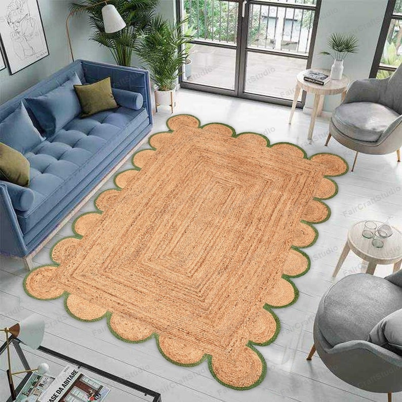 May include: A light brown jute rug with a scalloped edge and green trim. The rug is laid out on a light wood floor in a living room setting.