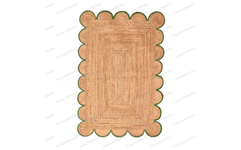 May include: A natural fiber rug with a scalloped border in a green color. The rug has a woven texture and a rectangular shape.