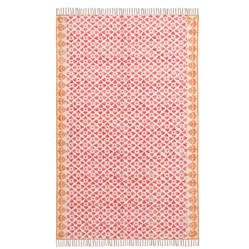 May include: A rectangular rug featuring a repeating floral pattern in red and white. The rug has a cream-coloured background with a symmetrical design. The edges are bordered with an orange floral pattern and finished with fringe.
