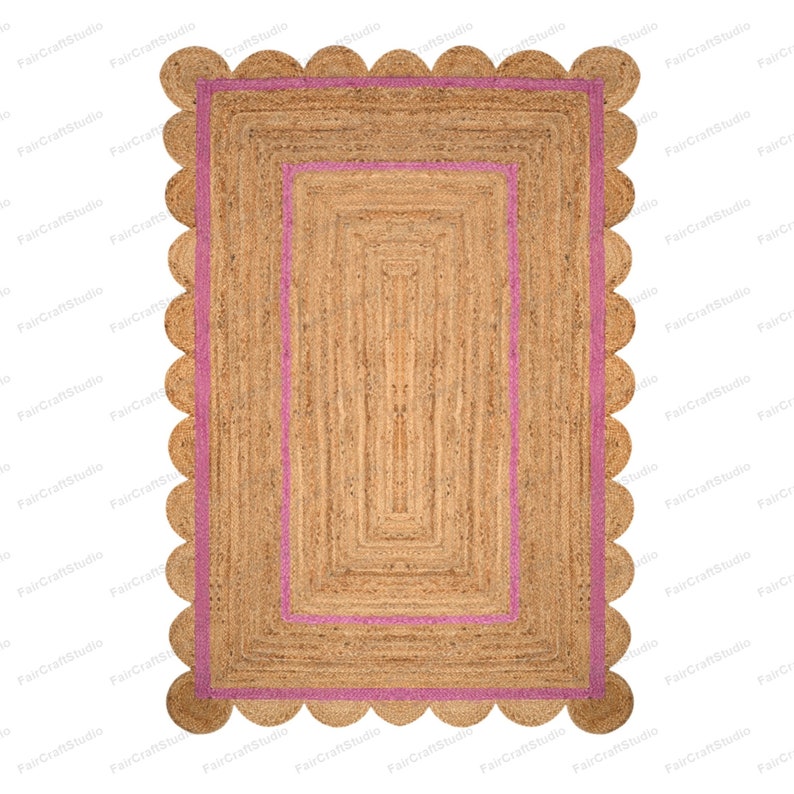 May include: A rectangular jute rug with a pink border and a scalloped edge. The rug has a woven texture and a natural brown color.