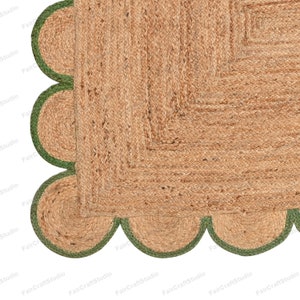 May include: A square jute rug with a green border. The border is made of a series of rounded shapes.