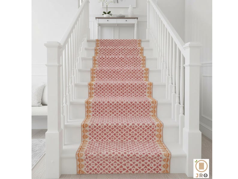 May include: A stair runner featuring a repeating heart pattern in red and cream. The runner is edged with a gold and cream design. The stairs are white with white banisters. The runner adds a decorative touch to the staircase.
