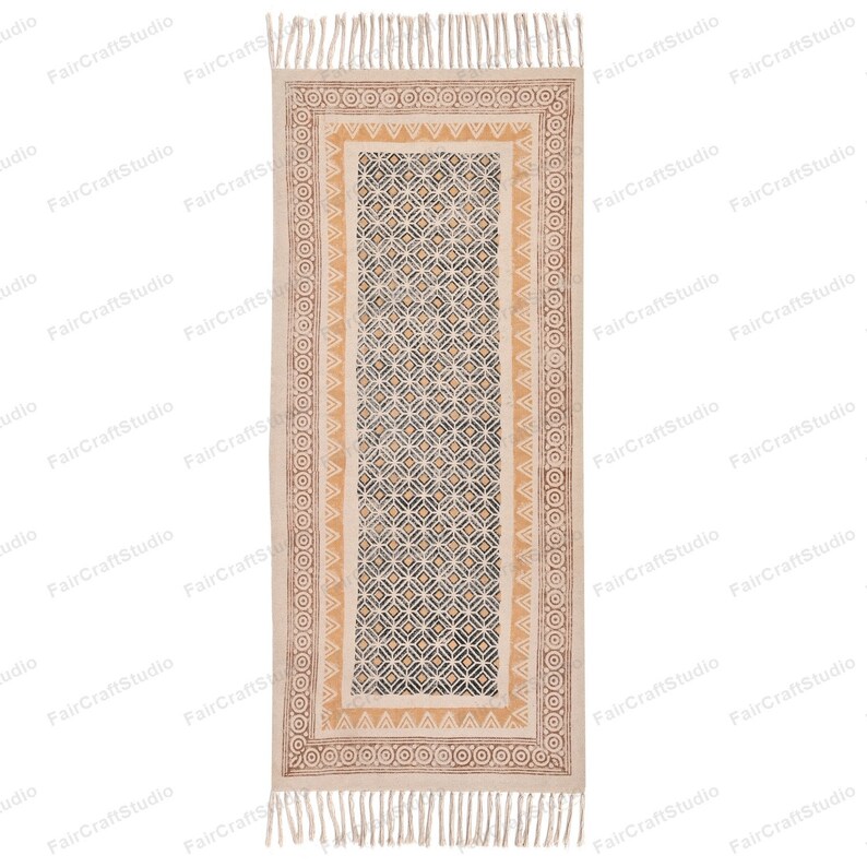 May include: A beige and brown patterned runner rug with a geometric design. The rug has a fringe on both ends.