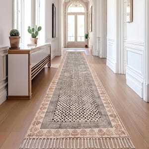 Può includere: Un lungo tappeto runner rettangolare con un motivo geometrico nei toni del grigio, beige e marrone. Il tappeto presenta un motivo ripetuto a diamante e floreale, con un bordo a frange. Il tappeto è posto in un corridoio.