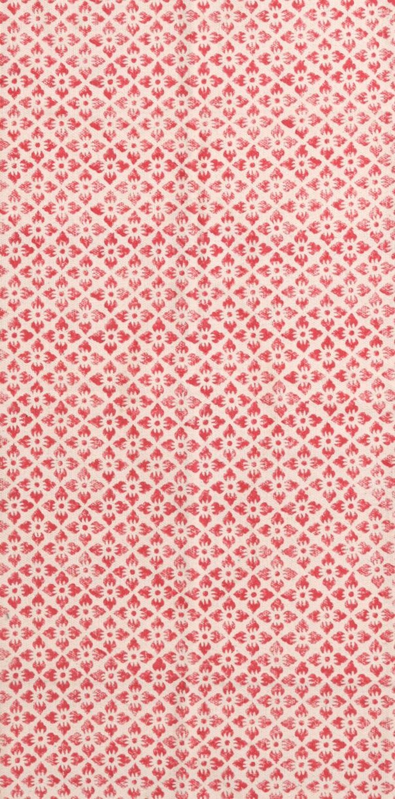 May include: A textile featuring a repeating pattern of red floral motifs on a cream background. The design is arranged in a diamond grid, creating a textured appearance. This fabric is suitable for various craft projects.