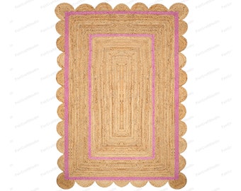 May include: A natural fiber rug with a pink border and scalloped edges. The rug has a woven texture and a rectangular shape.
