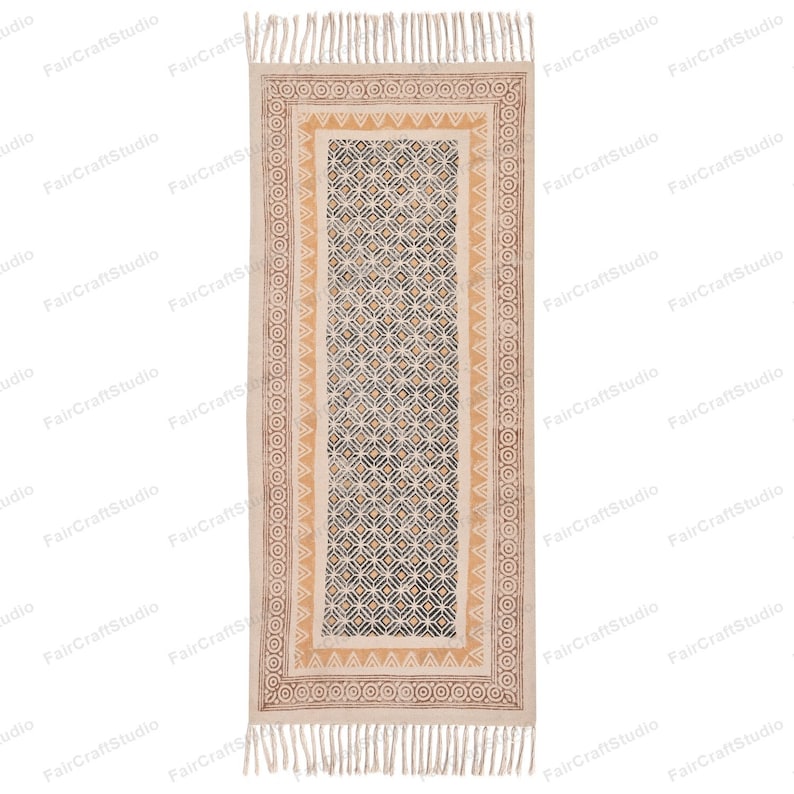 May include: A beige and brown patterned runner rug with a geometric design. The rug has a fringe on both ends.