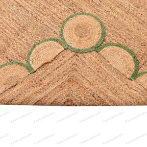 May include: A natural fiber rug with a woven texture and a green trim. The rug has a geometric pattern with rounded edges.