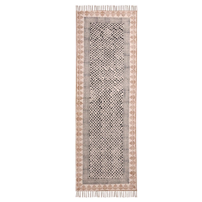 Puede incluir: Alfombra rectangular estampada, con fondo crema y dise&ntilde;o geom&eacute;trico repetido en blanco y negro. Borde gris y borde decorativo marr&oacute;n, con flecos en los extremos. Ideal para pasillo o entrada, con unos 200 cm de largo.