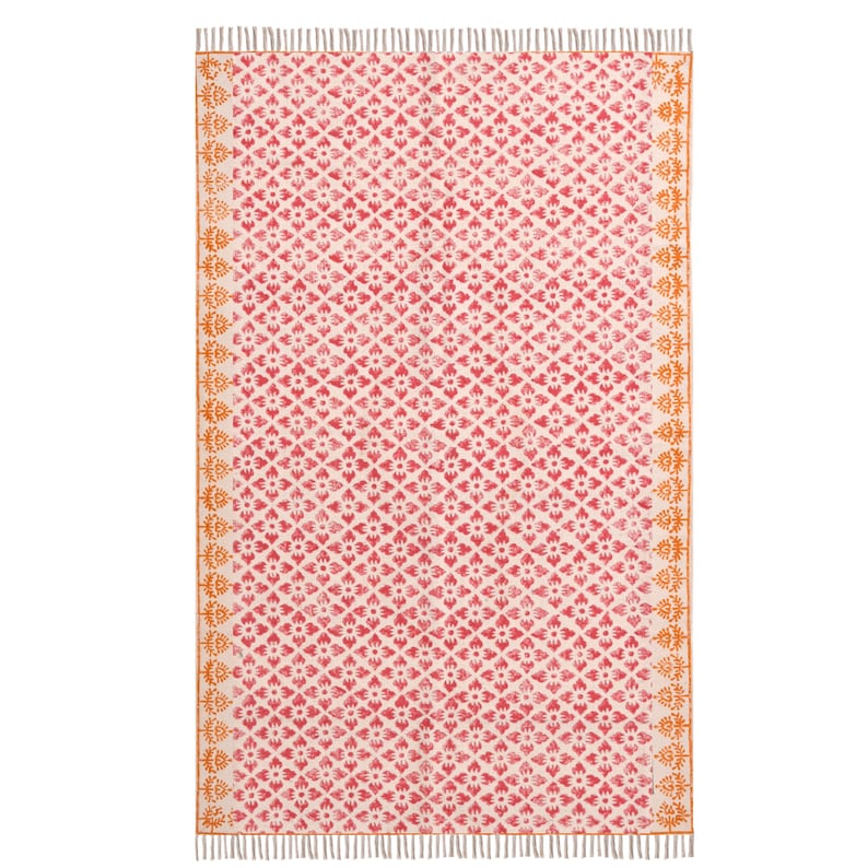 May include: A rectangular rug featuring a repeating floral pattern in red and white. The rug has a cream-coloured background with a symmetrical design. The edges are bordered with an orange floral pattern and finished with fringe.