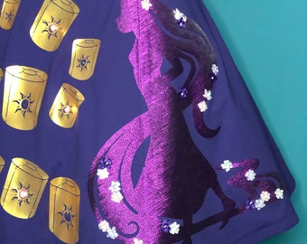 May include: Purple skirt with a silhouette of a woman with long hair and gold lanterns printed on it. The skirt has white and purple flowers sewn on it.