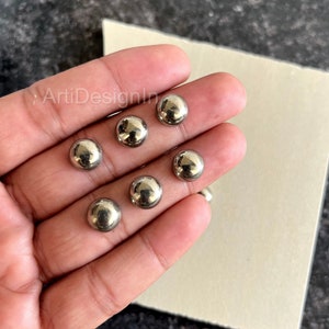 Può includere: Sette sfere di metallo argentate, di circa 2,5 cm di diametro, sono mostrate in una mano.