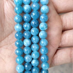 Könnte beinhalten: Eine Strähne blauer Aquamarinperlen mit leicht trübem Aussehen, die auf einer Hand übereinander liegen.