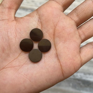 May include: Four round, dark brown, ceramic tiles.