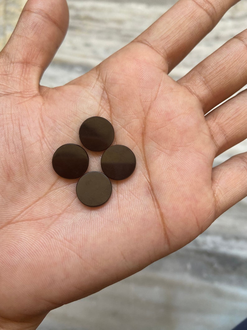 May include: Four round, dark brown, ceramic tiles.