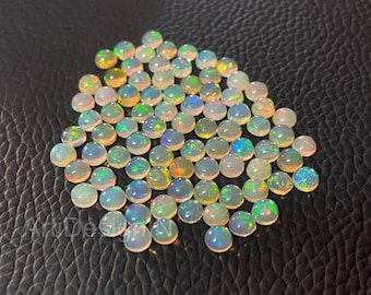 May include: A pile of round, iridescent opal gemstones in various shades of white, green, and blue. The opals are smooth and polished, with a slight sheen.
