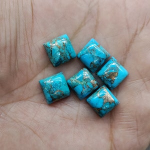 Puede incluir: Seis cabujones cuadrados de turquesa con motas doradas. Los cabujones son de un color azul vibrante y tienen una superficie lisa y pulida.