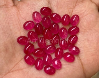 May include: A collection of oval-shaped, bright pink gemstones. The gemstones are smooth and polished, with a glossy finish.
