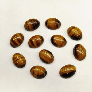 May include: Twelve oval-shaped tiger's eye cabochons in various shades of brown and gold. The stones are smooth and polished, with a subtle sheen.
