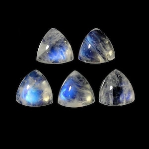 Peut inclure: Six cabochons de pierre de lune blanche irisée de forme triangulaire. Les pierres ont un reflet bleu.