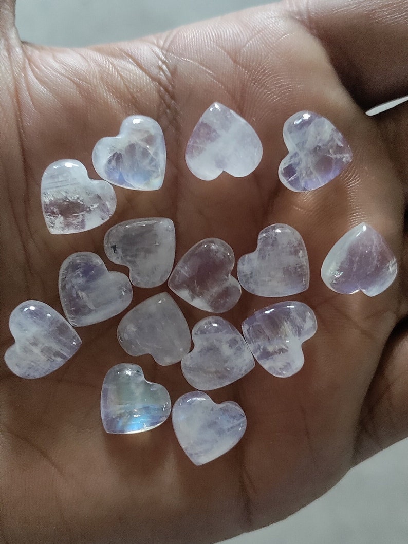 May include: A collection of 12 white heart-shaped moonstone crystals. The crystals are translucent and have a slight iridescent sheen.