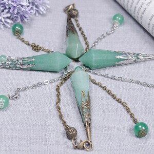 Può includere: Cinque pendoli di cristallo verde con catene ornate in argento e bronzo. Ogni pendolo ha una punta di cristallo verde e una parte superiore in metallo decorativa.