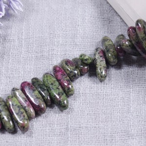 Peut inclure: Un brin de perles de pierres précieuses vertes et roses, chaque perle est de forme ovale et présente un motif marbré.