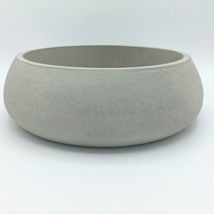 May include: A large, round, white ceramic bowl with a textured surface.