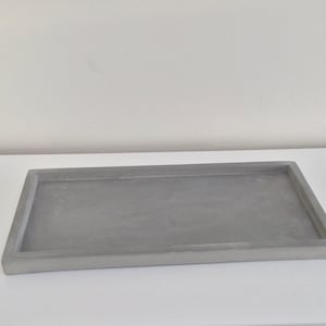 May include: A rectangular grey concrete tray with slightly rounded edges.