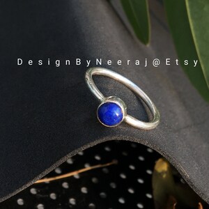 May include: A silver ring with a blue lapis lazuli gemstone. The ring is simple and elegant, perfect for everyday wear.